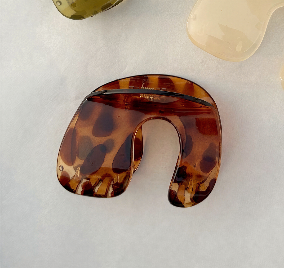 A brown, spotted object resembling a piece of jewelry or a decorative item is shown on a white surface.