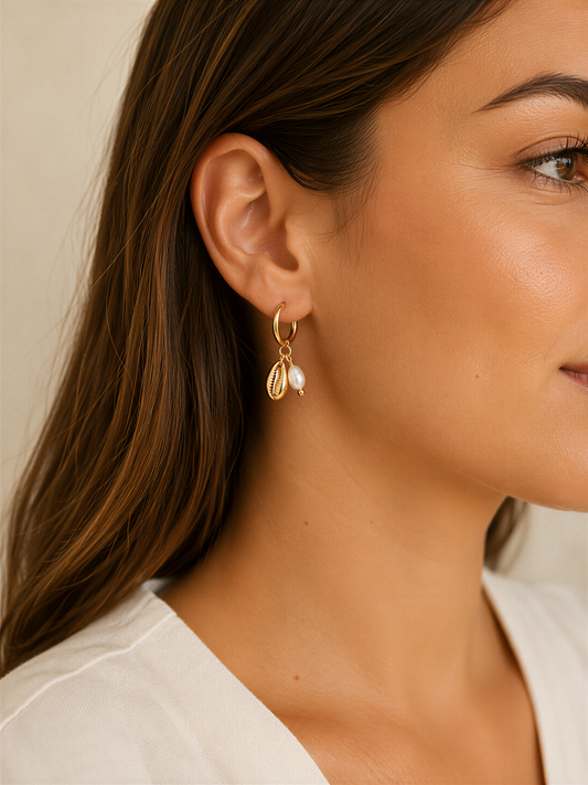 A close-up of a woman's face wearing a pair of gold earrings with pearls and charms hanging from them.