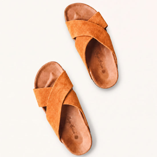 A pair of brown suede sandals with a cross-over design.