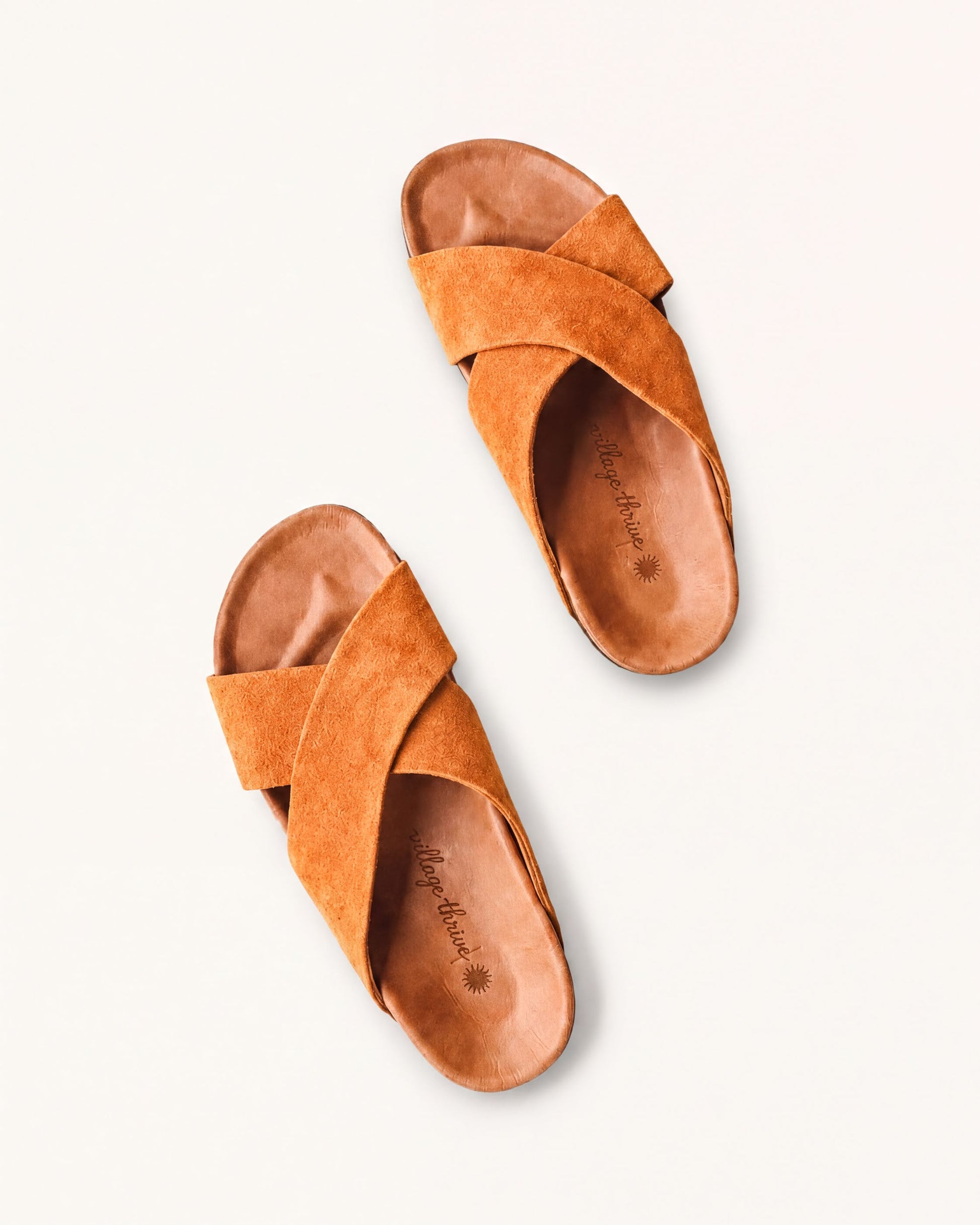 A pair of brown suede sandals with a cross-over design.